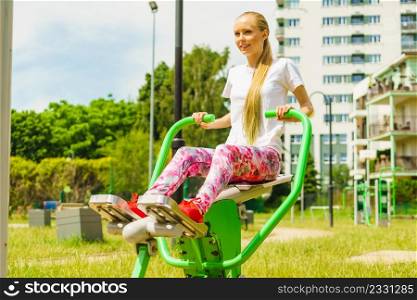 Young woman working out in outdoor gym. Girl making exercises and training at public sport area in city park. Healthy lifestyle.. Girl doing legs exercise at outdoor gym area