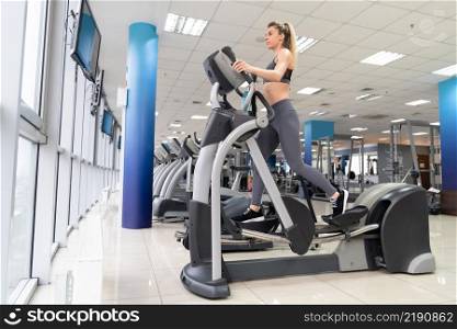 Young woman working out on orbi track at gym exercising inside fitness center. Young woman working out on orbi track at gym exercising