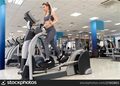 Young woman working out on orbi track at gym exercising inside fitness center. Young woman working out on orbi track at gym exercising