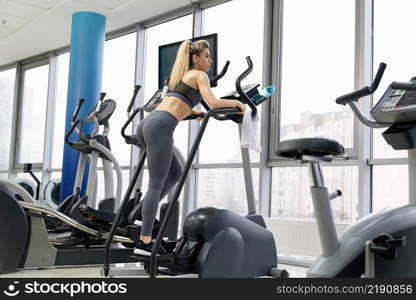 Young woman working out on stepper at gym exercising inside fitness center. Young woman working out on stepper at gym exercising