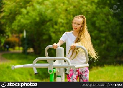 Young woman working out outside. Girl making exercises and training on public equipment in outdoor gym at park. Healthy lifestyle.. Female doing exercise in outdoor gym