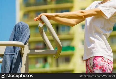 Young woman working out outside. Girl making exercises and training on public equipment in outdoor gym at park. Healthy lifestyle.. Female doing exercise in outdoor gym