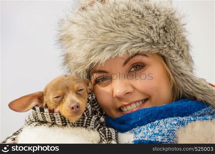 Young woman wrapped her best friend little dog in warm blanket scarf to warm him in cold winter day. Animal protection save. Adoption concept. Woman hug warming her dog in cold day