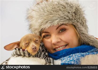 Young woman wrapped her best friend little dog in warm blanket scarf to warm him in cold winter day. Animal protection save. Adoption concept. Woman hug warming her dog in cold day