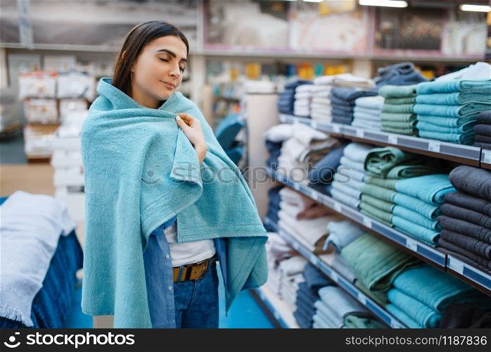 Young woman wrapped herself in a towel, bed linen store. Female person buying home goods in market, lady in bedding shop. Woman wrapped in a towel, bed linen store