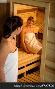 Young woman wrapped in towel posing in front of the sauna room