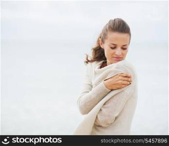 Young woman wrapping in sweater on coldly beach