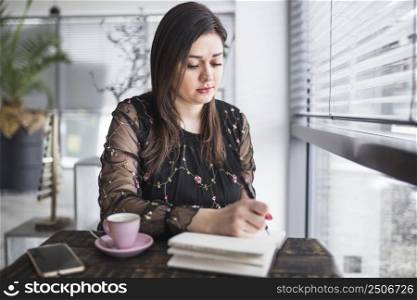 young woman writing diary restaurant