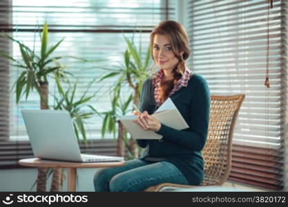 Young woman writing in a notebook with a blank cover