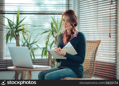 Young woman writing in a notebook with a blank cover