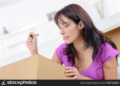 Young woman writing on a cardboard box