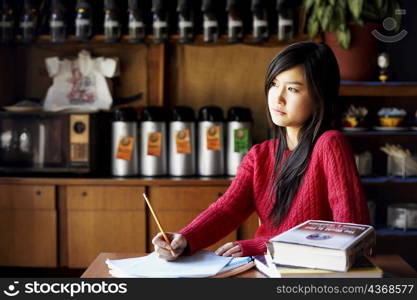 Young woman writing on a sheet of paper and thinking