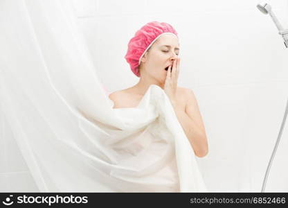 Young woman yawning while having shower at morning