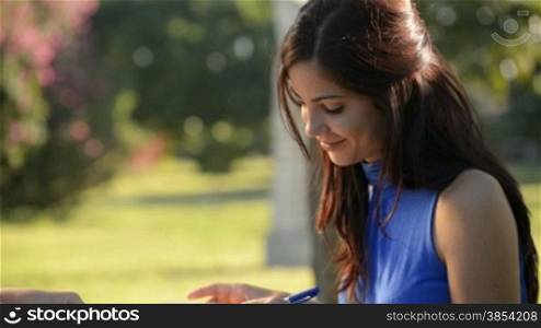 Young women and education, two female friends study for college exam in park. Sequence of medium and wide shots
