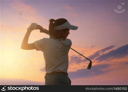 Young Women Asia player golf swing shot on course with sunset sky twilight background. exercise and health concept. Golf practice to be a professional golfer