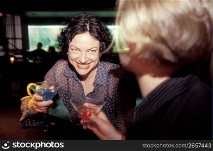 Young women at bar with drinks, smiling