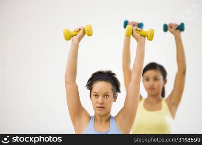 Young women at gym lifting hand weights.