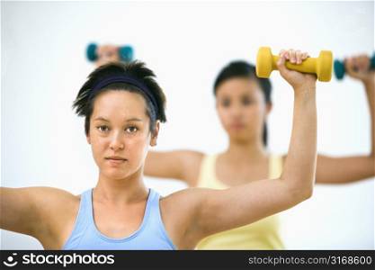 Young women at gym lifting hand weights.