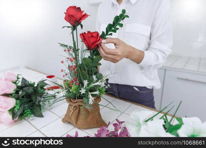 young women business owner florist making or Arranging Artificial flowers vest in her shop, craft and hand made concept.