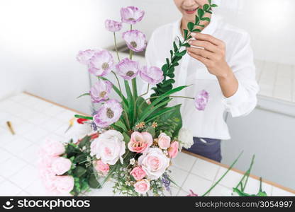 young women business owner florist making or Arranging Artificial flowers vest in her shop, craft and hand made concept.