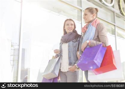 Young women carrying shopping bags by store