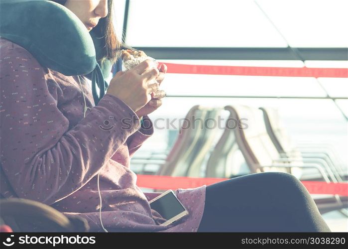 young women eating snack while waiting for flying at airport win. young women eating snack while waiting for flying at airport window
