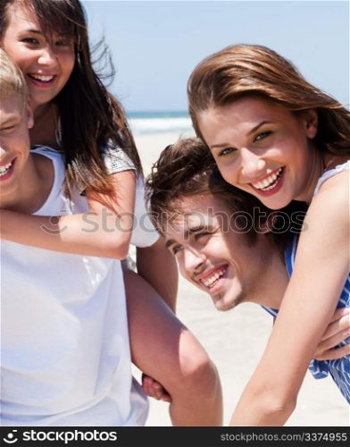 Young women enjoying piggyback ride by the beach
