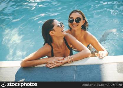 Young women having fun by the pool at hot summer day