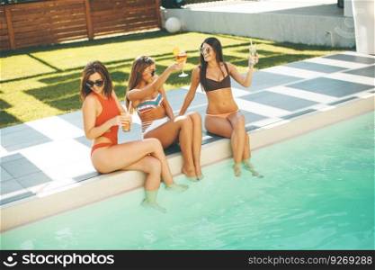 Young women having fun by the pool at hot summer day