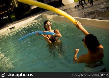 Young women having fun in the swimming pool at hot summer day