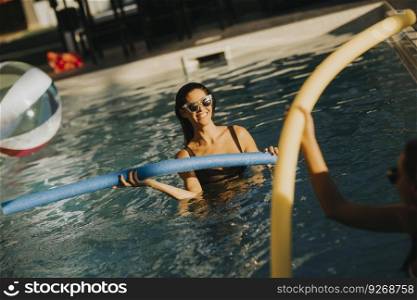 Young women having fun with swimming pool noodles at hot summer day