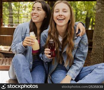 young women holding fresh juice bottles laughing