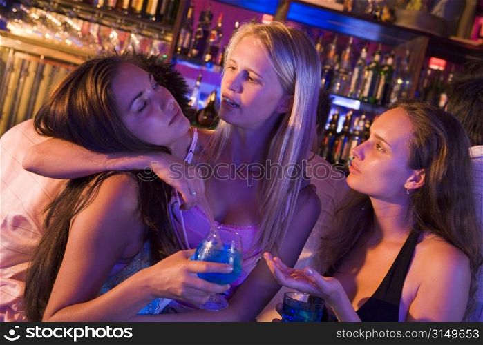 Young women in a bar with one drunk friend passed out