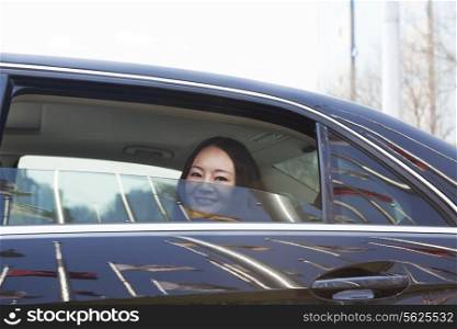 Young women in back seat of car looking out of window.