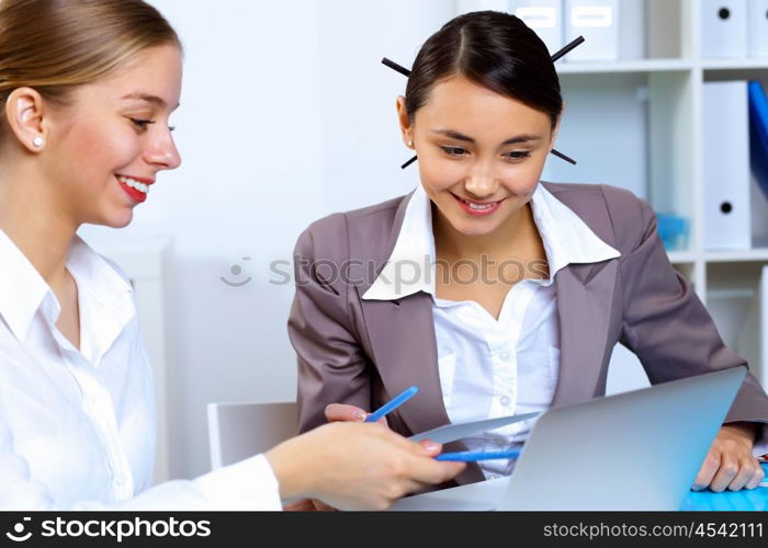 Young women in business wear working in office together