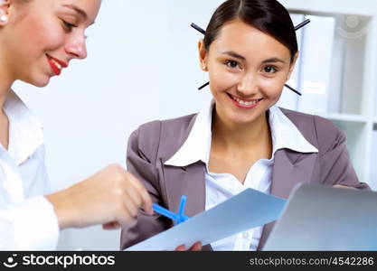 Young women in business wear working in office together