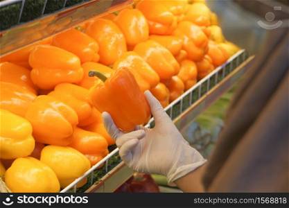 young women in protective gloves holding capsicum at retail store.. young women in protective gloves holding capsicum at retail store