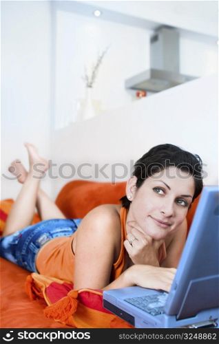 Young women is resting on the couch and surfing the internet on her laptop computer.