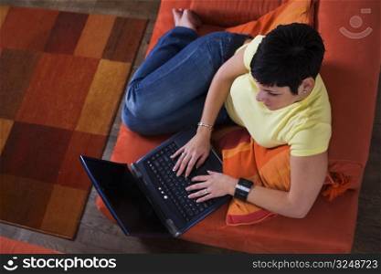Young women is using a laptop computer is her comfortable living room.