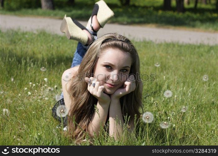 Young women lying on green grass in dandelions