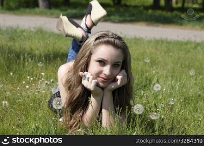 Young women lying on green grass in dandelions
