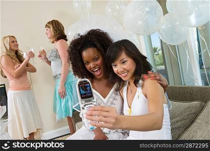 Young women photographing themselves using mobile phone at bridal shower