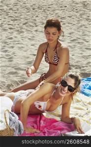 Young women putting on sun tan lotion
