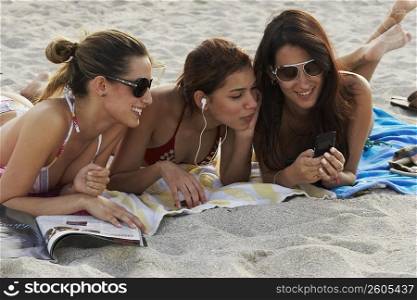 Young women reading magazines and sunbathing on beach
