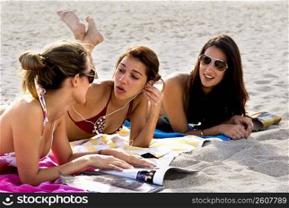 Young women reading magazines and sunbathing on beach