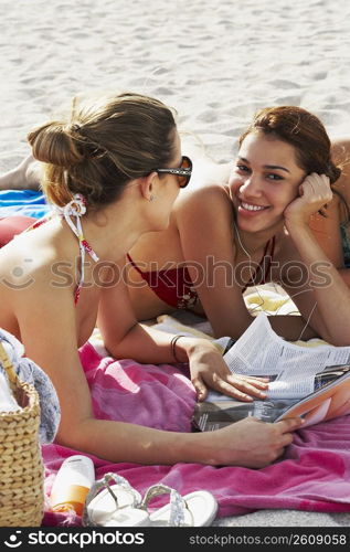 Young women reading magazines and sunbathing on beach