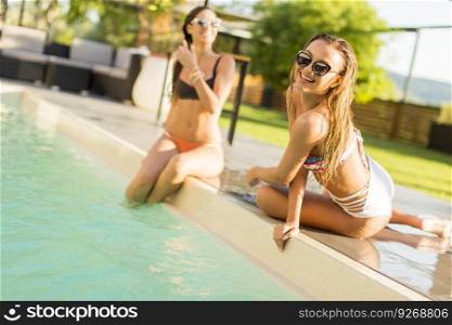 Young women relaxing by the pool at hot summer day