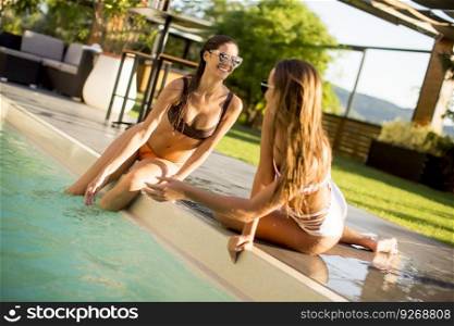 Young women relaxing by the pool at hot summer day