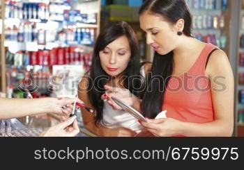 Young Women Shopping for Cosmetics in Beauty Department, Testing Lip Gloss