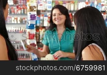 Young women shopping in cosmetics store, shop assistant offers goods for body care